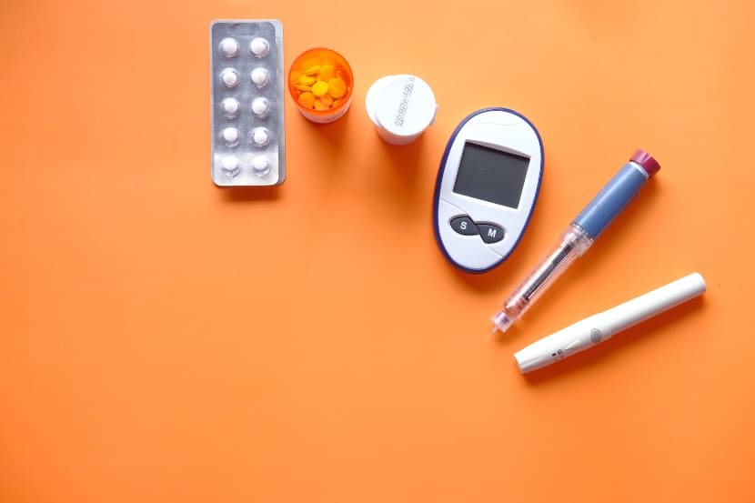 Insulinstift, diabetische Messgeräte und Tabletten auf orangefarbenem Hintergrund